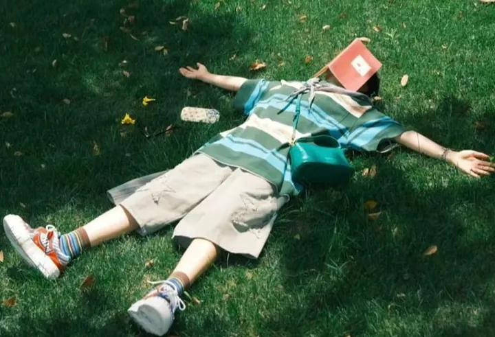 A boy lying on the ground with a book over his head